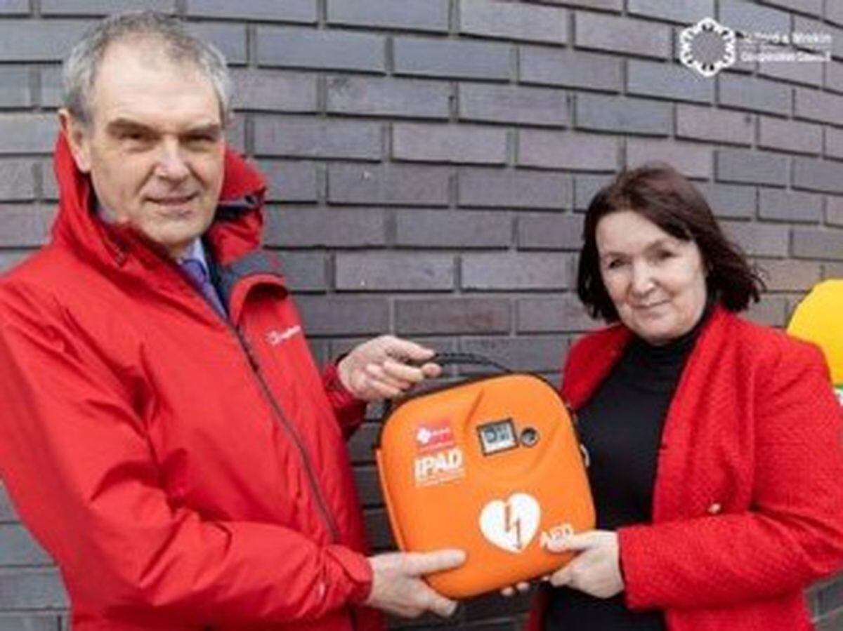 Councillors Andy Burford and Kelly Middleton with one of the defibrillators