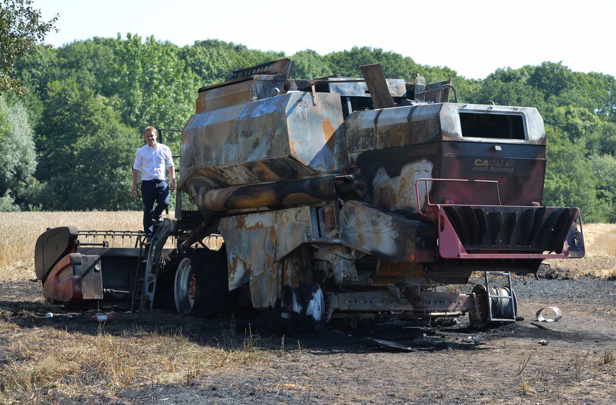 Farmer Tim Ashton with the burnt-out husk of his combine harvester