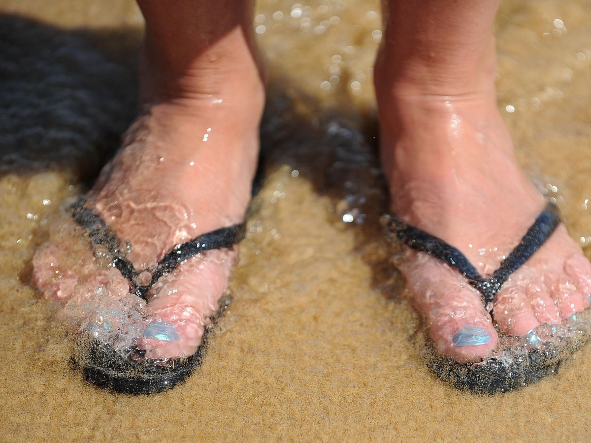 Feet in flip flops on a beach