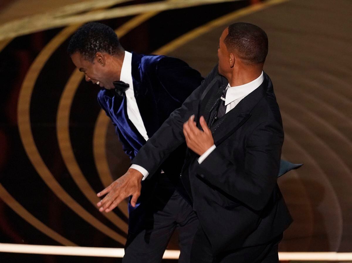Will Smith, right, hits presenter Chris Rock on stage while presenting the award for best documentary feature at the Oscars on Sunday, March 27, 2022, at the Dolby Theatre in Los Angeles. (AP Photo/Chris Pizzello).
