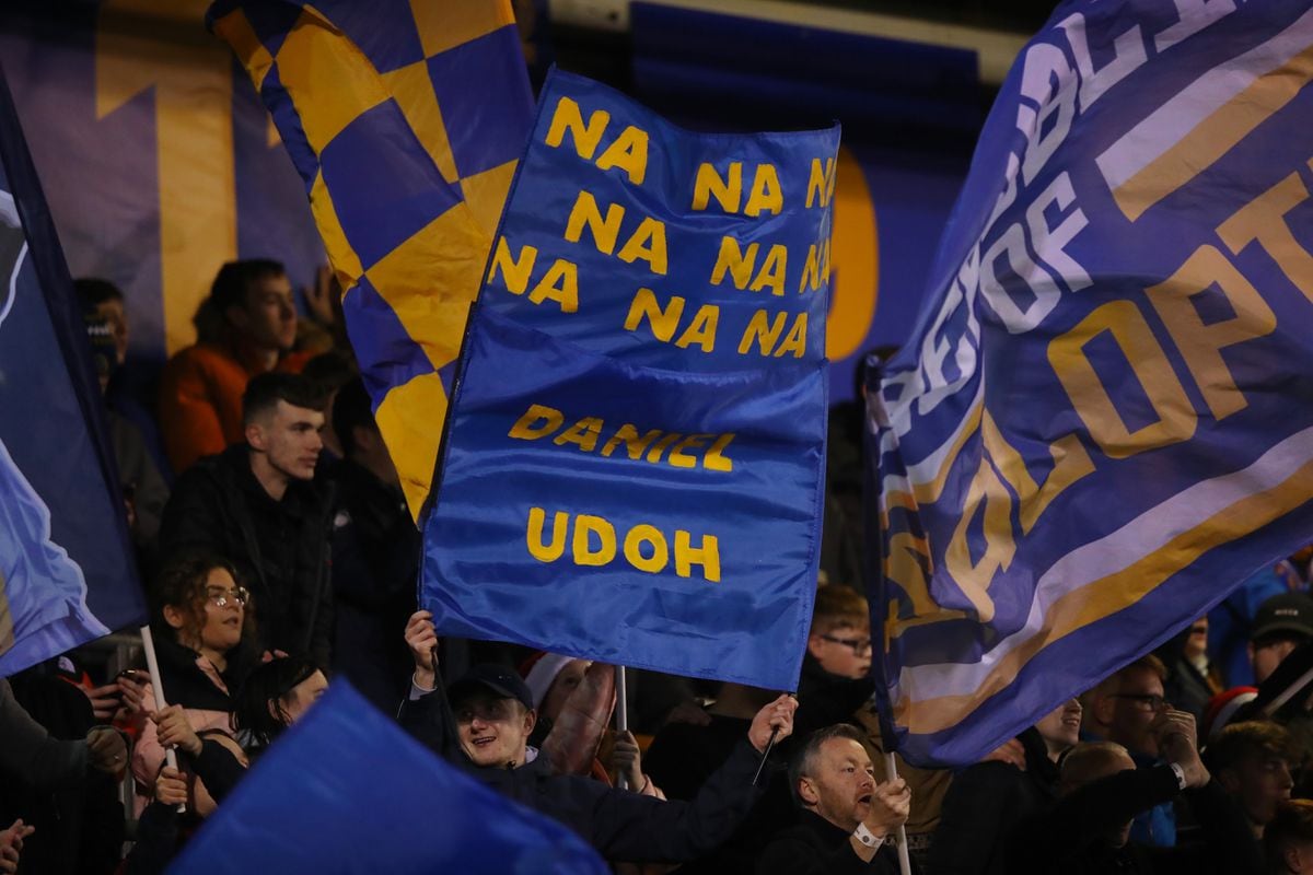 A Dan Udoh flag is waved by fans in the standing area of the South Stand. (AMA)