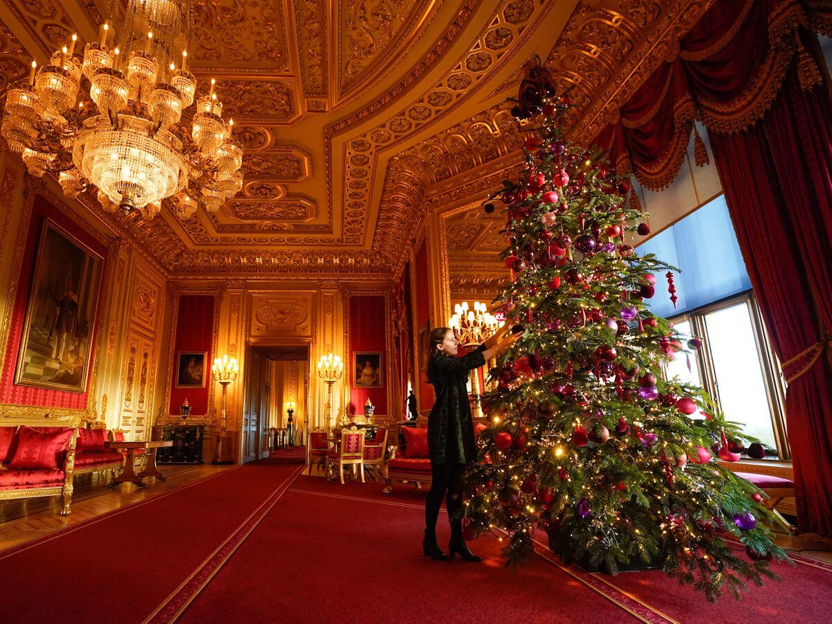 A member of the Royal Collection Trust staff puts the finishing touches to a Christmas tree in the Crimson Drawing Room, during a photo call for Christmas decorations at Windsor Castle