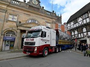 A fun fair lorry slowly makes it's way through the narrow streets of Ludlow and past the Buttercross ready for the May Fair..