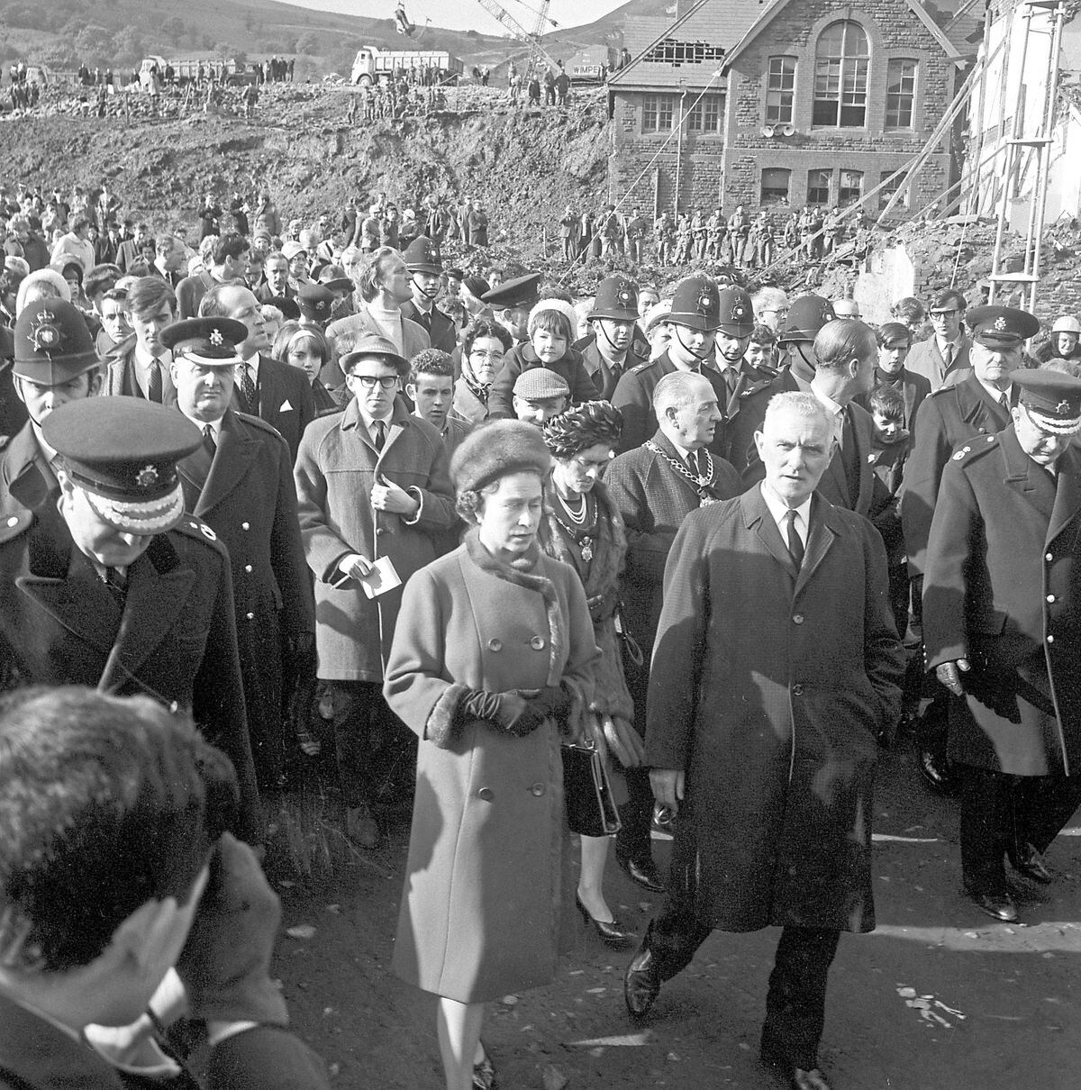 Queen Elizabeth II and the Duke of Edinburgh (head turned, right) on the site of the tragic Pantglas Junior School, during their visit to devastated Aberfan, South Wales. Right of the Queen is Councillor Jim Williams, who lost seven members of his family in the coal-tip disaster