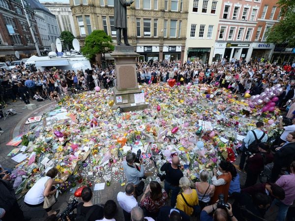 Crowds look at the floral tributes after a minute’s silence in St Ann’s Square, Manchester, to remember the victims of the terror attack in 2017