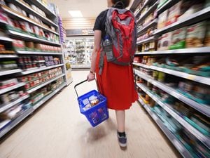 A shopper walking through the aisle of a supermarket. 