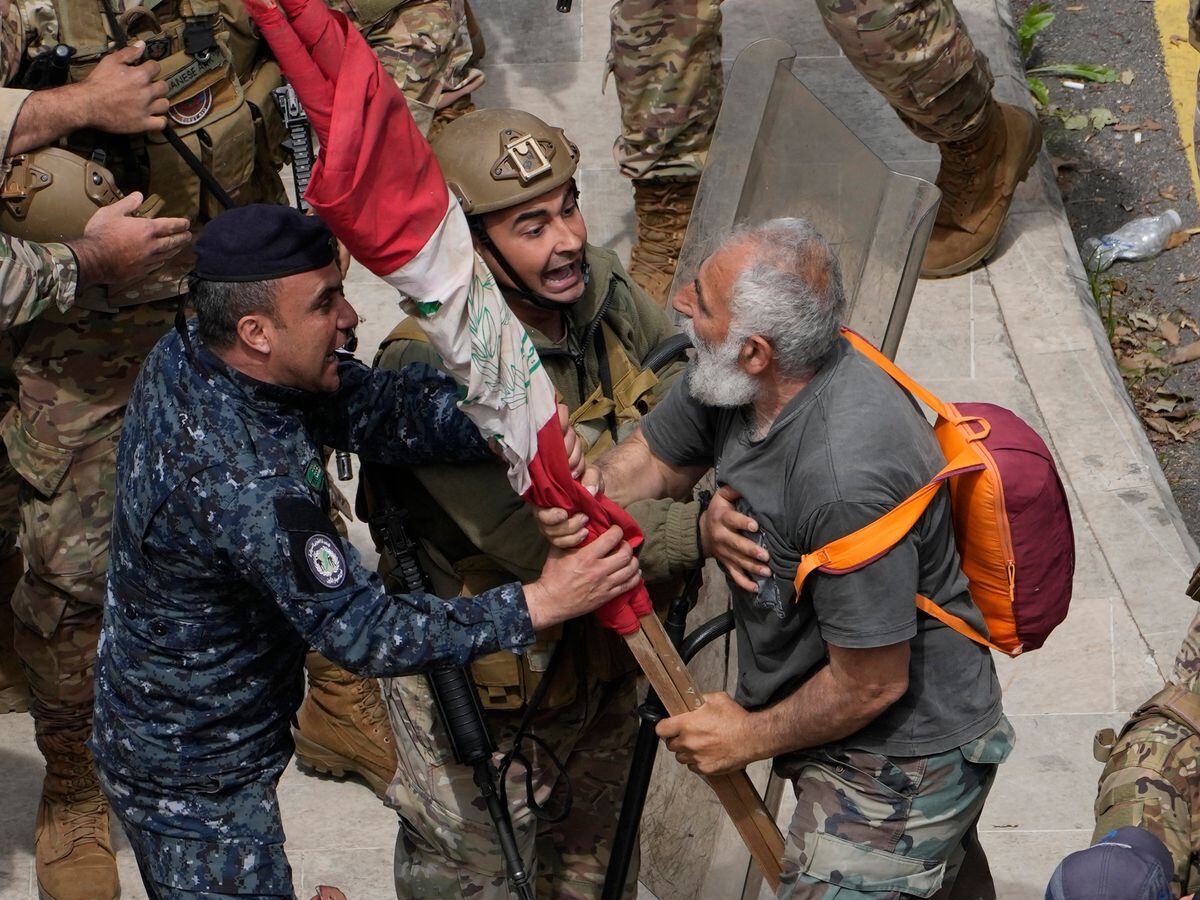 A retired army soldier, right, protests demanding better pay and clashes with Lebanese army and riot police in Beirut