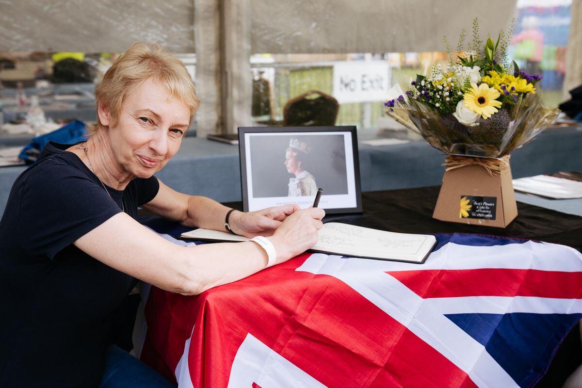 Volunteer Melanie Clemmey with a book of condolence in memory of Queen Elizabeth II..