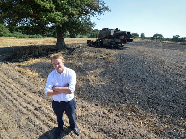 Farmer Tim Ashton with the burnt-out husk of his combine harvester and the emergency firebreak he had to make