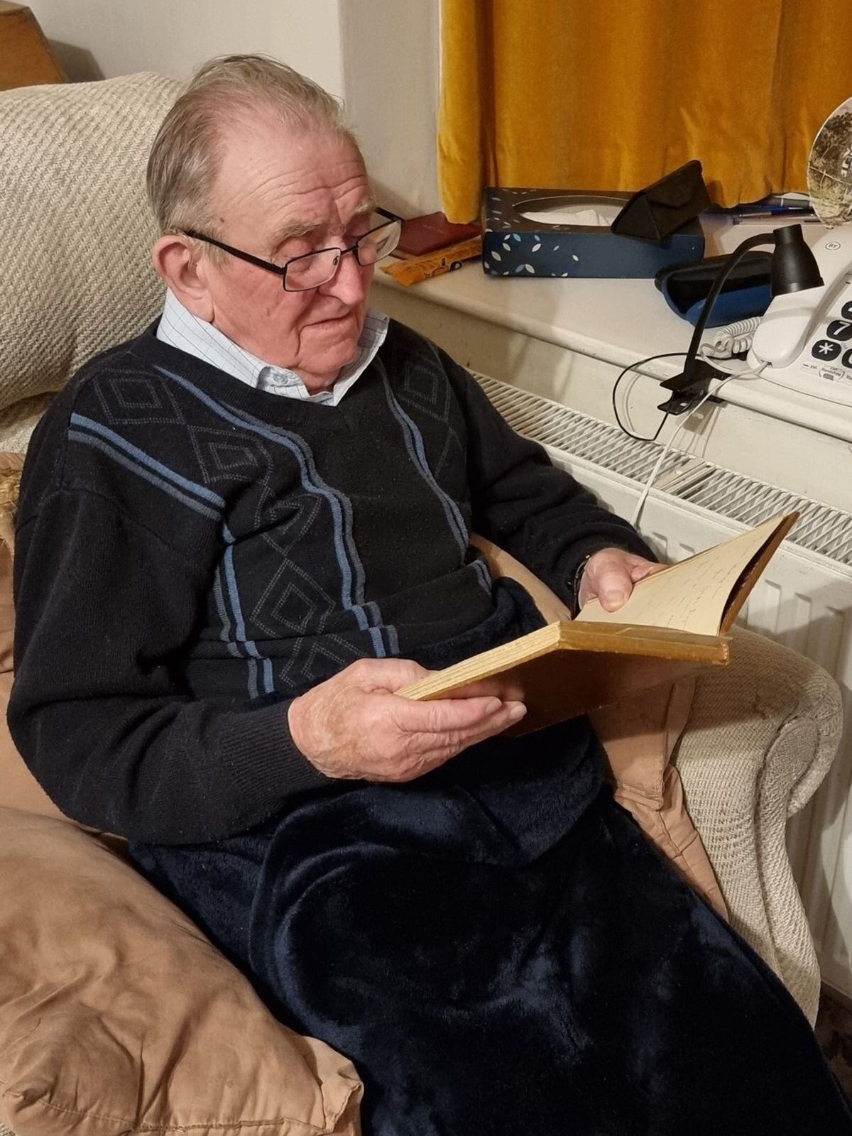 John Whittingham pictured at home reading a first edition of Captain Geoffrey Dugdale's book: 'Langemark' and 'Cambrai' - A War Narrative 1914-1918