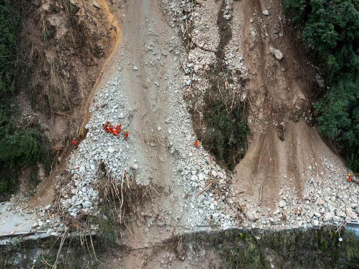 Rescuers transfer a villager through a damaged mountain road near Moxi Town of Luding County, south-west China's Sichuan Province