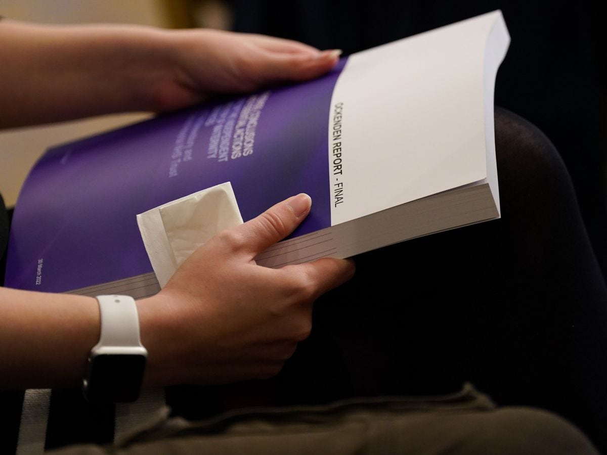 A woman holds a copy of the Ockenden Report
