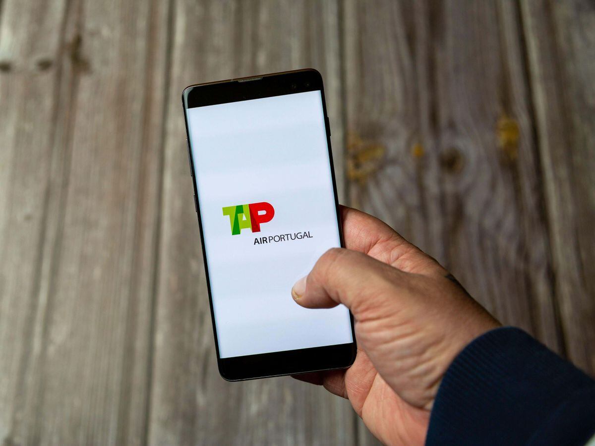 A Mobile phone or Cell phone being held in a hand showing the Tap Air Portugal app on screen