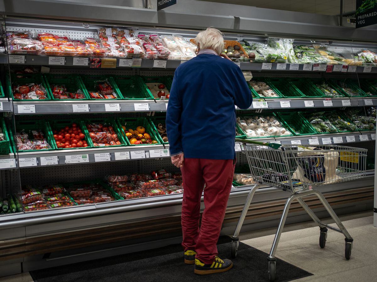 A shopper looks at salad vegetables in a branch of Waitrose