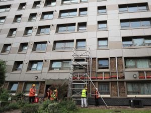 Workmen start to remove cladding on a building