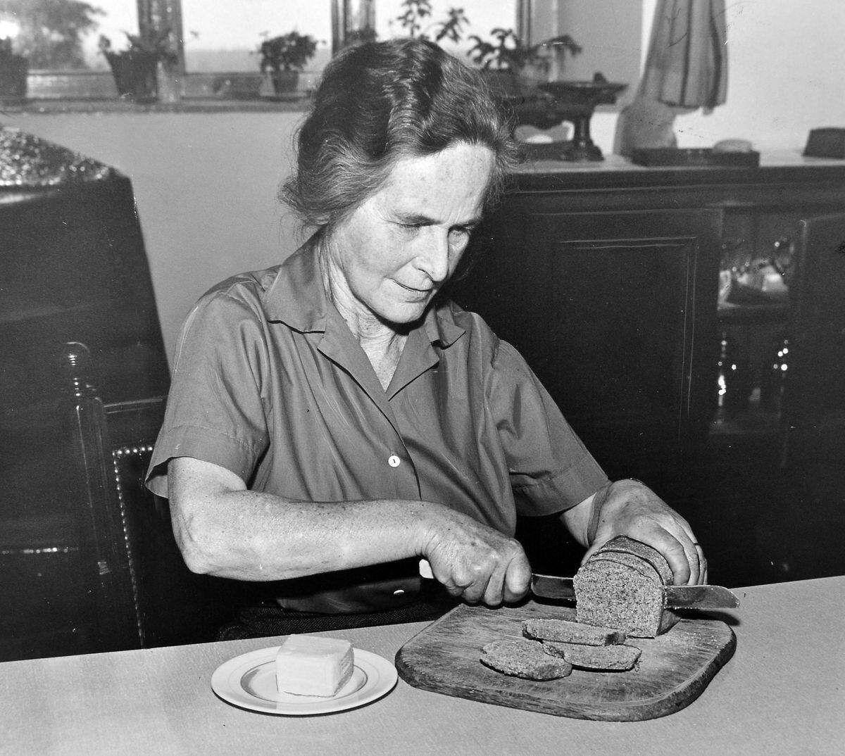 Dora Mayall cuts a slice of the organic bread in 1960.