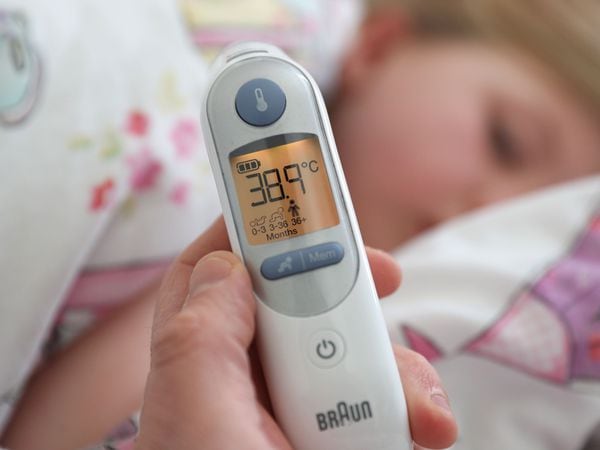 A temperature of 38.9 degrees is visible on a digital ear thermometer after being taken from a poorly child