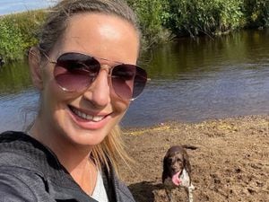 Nicola Bulley takes a selfie near a river with a dog behind her