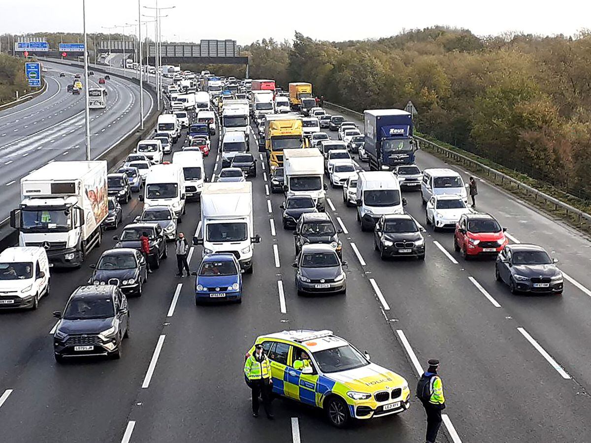A police patrol car parked in front of lanes of stationary traffic on the motorway.