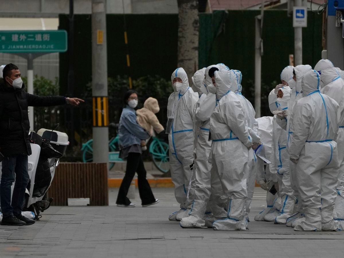 Workers in protective gear gather for their duties in Beijing, November 2022. Photo: AP/Andy Wong