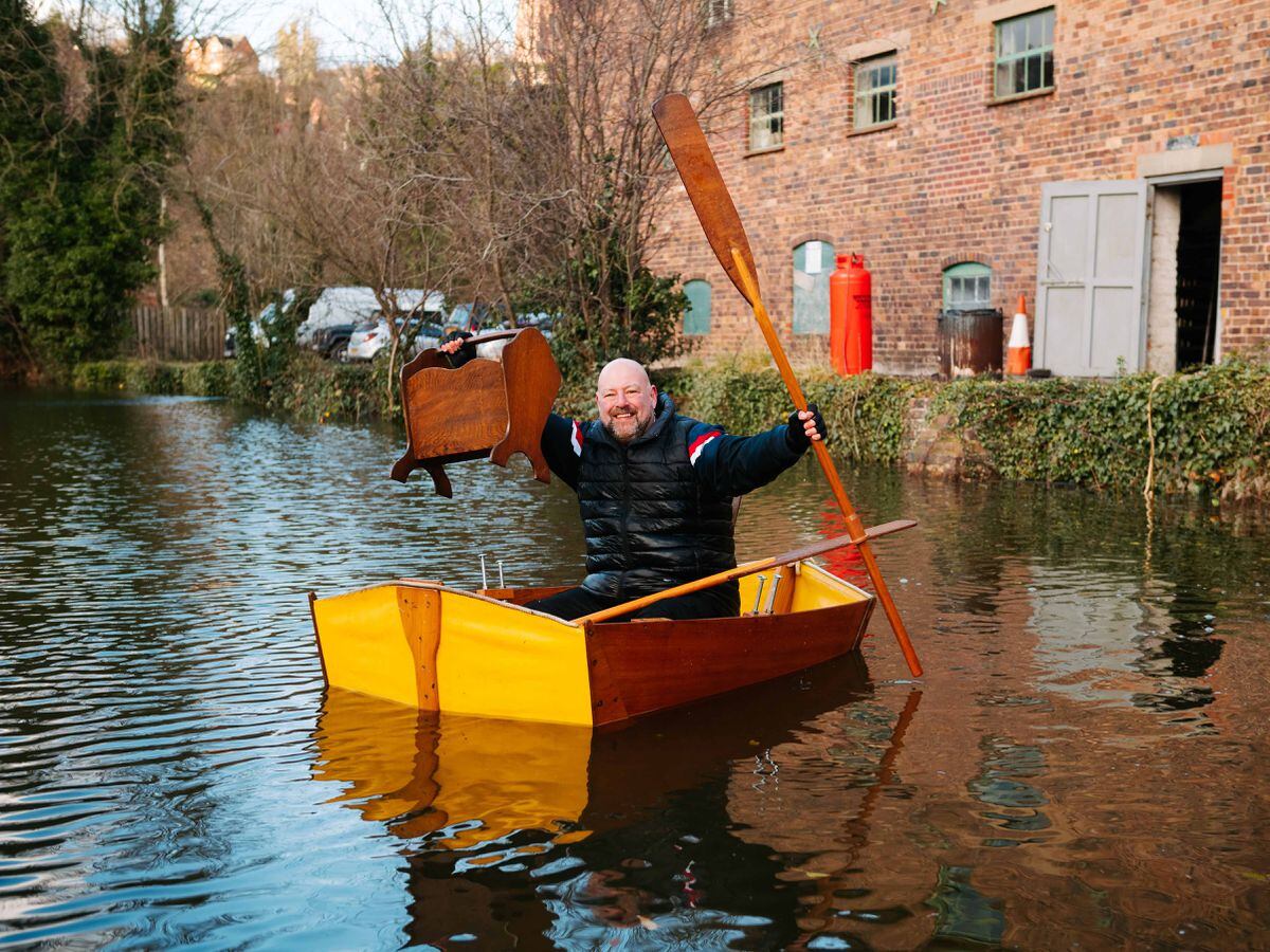 Stuart Bowen rows across the flooded car park at The Old Mill Antiques Centre in Bridgnorth