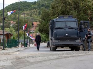 A local Serb man walks past Kosovo police officers securing the area around the Banjska monastery in the village of Banjska, Kosovo