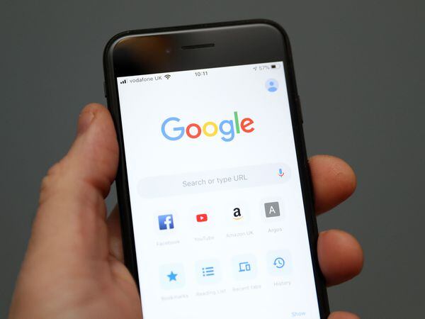 A person holding a phone and looking at Google