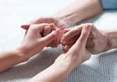 Stock photo of an older person holding hands with a carer